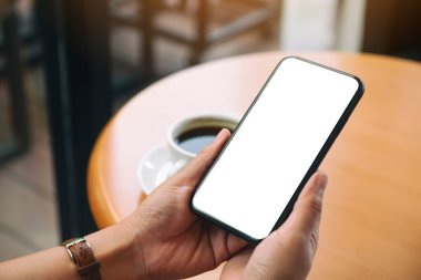 Boş masaüstü ekranı olan siyah cep telefonunu tutan ellerin görüntüsü