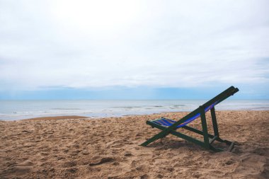 Deniz kenarında mavi gökyüzü arka planlı tek bir plaj sandalyesi.