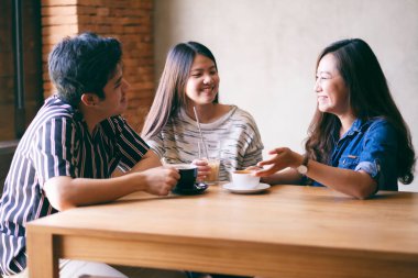 Üç kişinin yakın plan görüntüsü kafede sohbet ve kahve içmekten keyif alıyordu.