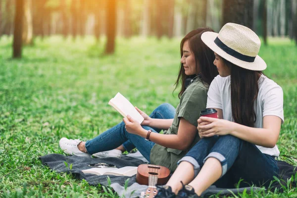 Ormanda otururken birlikte kitap okuyan iki kadın.
