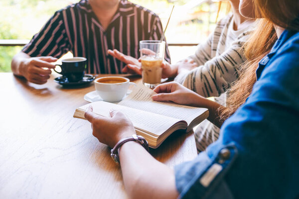 A group of people enjoyed talking, reading and drinking coffee together in cafe