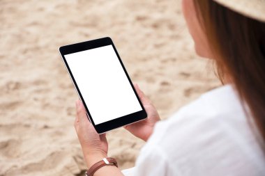 Plaj sandalyesinde otururken elinde boş masaüstü ekranı olan siyah bir tablet tutan bir kadının görüntüsü.