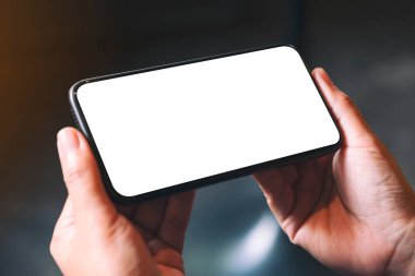 Boş masaüstü ekranı olan siyah cep telefonunu tutan ellerin görüntüsü