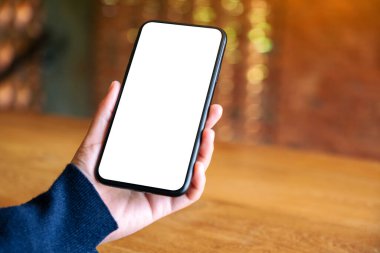 Kafede elinde siyah cep telefonu olan beyaz ekranlı bir kadının görüntüsü.