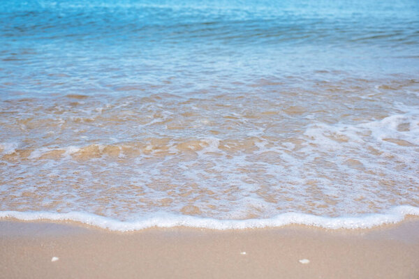 Closeup image of soft wave of blue sea on the white beach 