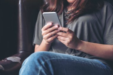 Elinde tutan, kullanan ve akıllı telefona bakan bir kadının yakın plan görüntüsü.