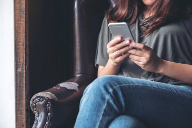 Elinde tutan, kullanan ve akıllı telefona bakan bir kadının yakın plan görüntüsü.