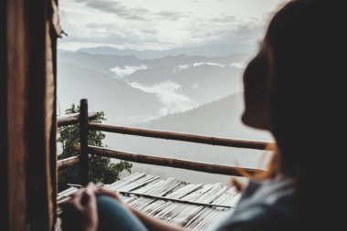 Sisli bir günde tek başına oturmuş dağları seyreden bir kadın.