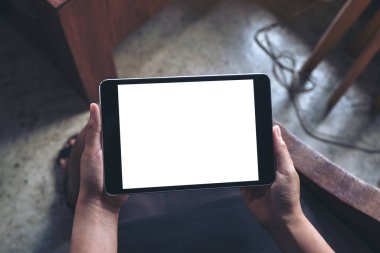 Boş beyaz masaüstü ekran ile siyah tablet bilgisayarını tutan bir kadının en üst görünüm görüntüsü 