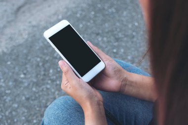 Sokakta otururken beyaz cep telefonunun siyah ekranlı görüntüsü.
