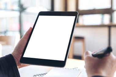 Ofisteki not defterlerine yazarken boş beyaz masaüstü ekran ile siyah tablet pc 'yi tutan ve kullanan ellerin görüntüsünü taklit et
