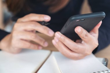 Çalışırken elinde tutan, kullanan ve akıllı telefona bakan bir kadının yakın plan görüntüsü