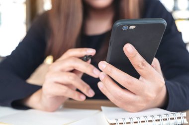 Çalışırken elinde tutan, kullanan ve akıllı telefona bakan bir kadının yakın plan görüntüsü