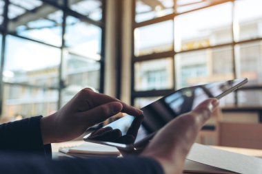 Ofisteki siyah tablet bilgisayar ekranını tutan ve işaret eden ellerin yakın plan görüntüsü