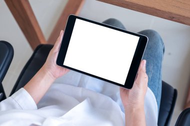 Sandalyede otururken elinde siyah tablet olan beyaz ekranlı bir kadının en üstteki görüntüsü