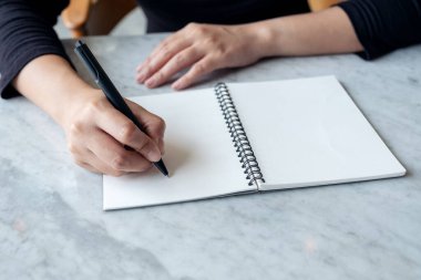 Masaya boş not defterine yazı yazan ellerin yakın plan resmi 