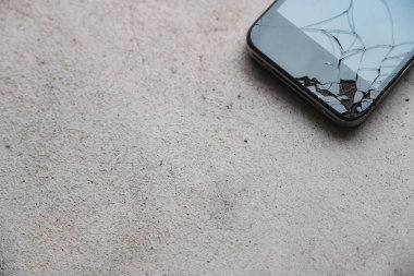 Yerde kırık bir cep telefonu var.