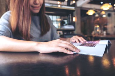 Modern kafede kitap okuyan Asyalı güzel bir kadının yakın plan görüntüsü. 