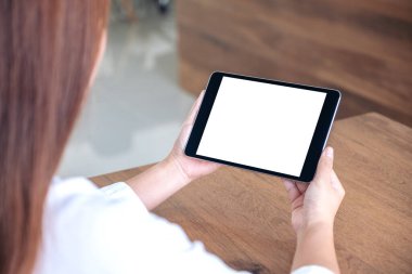 Ofiste otururken boş beyaz masaüstü ekranlı siyah tablet bilgisayar kullanan ve elinde tutan kadının görüntüsü