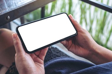 Kafede otururken elinde boş masaüstü ekran olan siyah cep telefonu tutan bir kadının görüntüsü