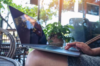 Dışarıda otururken bilgisayarın dokunduğu ve kullandığı ellerin yakın plan görüntüsü.