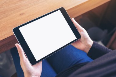 Sandalyede otururken elinde siyah tablet olan beyaz ekranlı bir kadının en üstteki görüntüsü
