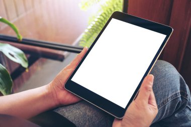 Kafede otururken elinde siyah tablet olan beyaz ekranlı bir kadının görüntüsü.