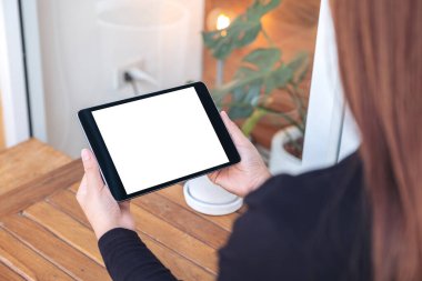 Siyah tableti elinde tutan ve beyaz ekranlı siyah tablete bakan bir kadının görüntüsü