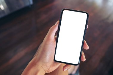 Üst görünümde oturan ve elinde beyaz ekranlı siyah cep telefonu tutan bir adamın görüntüsü   