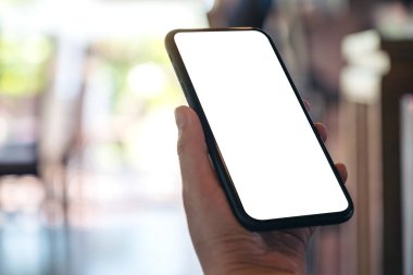 Boş beyaz ekranlı ve bulanık arkaplanlı siyah cep telefonlu el görüntüsü