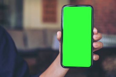 Boş esktop ekranlı ve arka planı bulanık siyah cep telefonunu tutan bir elin görüntüsü