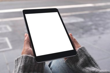 Açık havada boş beyaz masaüstü ekranı olan siyah tablet tableti tutan ve kullanan ellerin görüntüsünü taklit et