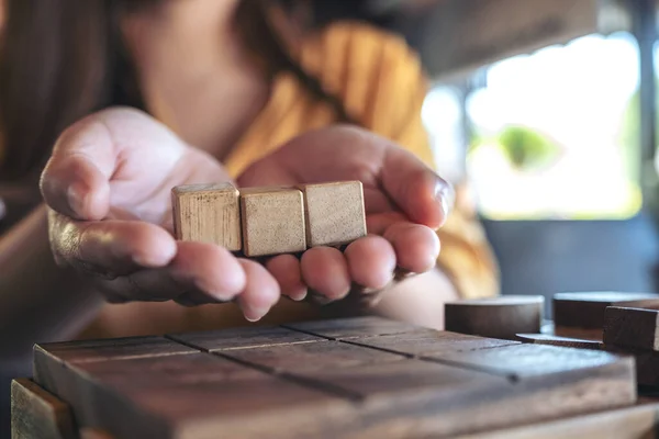 Руки Женщины Держатся Показывают Три Квадратных Деревянных Блока — стоковое фото