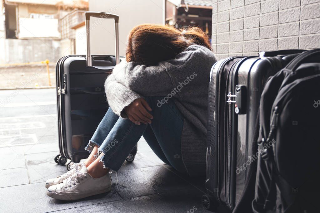 A woman sitting with feeling sad while traveling with a lot of baggages on the floor