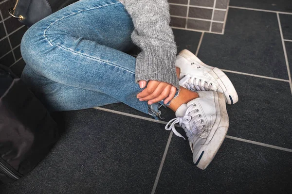 Närbild Kvinna Klädd Jean Och Vita Sneakers Röra Hennes Ben — Stockfoto