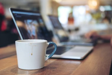 Laptop klavyesinde çalışan ve daktilo kullanan insanların ofis masasında kahve fincanı olan yakın plan görüntüleri.