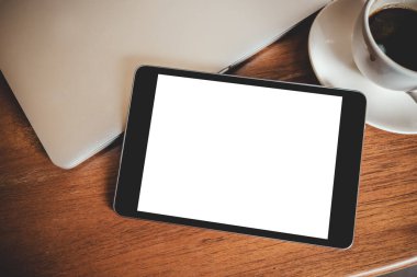 Masaüstü beyaz ekranlı, dizüstü bilgisayarı ve kahve fincanı tahtada olan siyah bir tabletin en üstteki görüntüsü