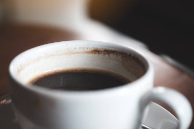 Kafedeki eski ahşap masada bir fincan sıcak kahvenin yakın plan görüntüsü.