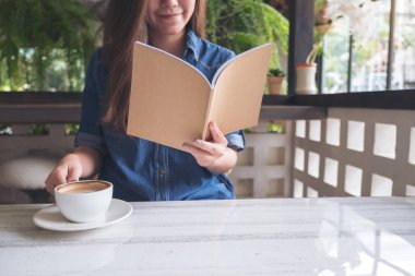 Modern kafede kahve içerken kitap okuyan Asyalı güzel bir kadının yakın çekimi. 