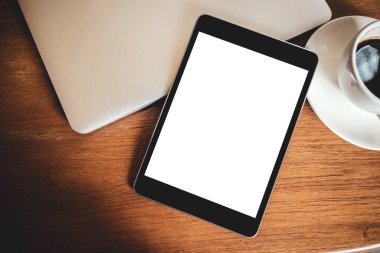 Masaüstü beyaz ekranlı, dizüstü bilgisayarı ve kahve fincanı tahtada olan siyah bir tabletin en üstteki görüntüsü