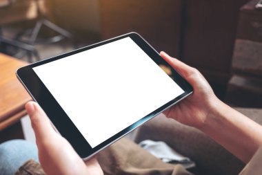 Kafede otururken siyah tableti beyaz masaüstü ekran ile tutan kadınların ellerinin görüntüsü