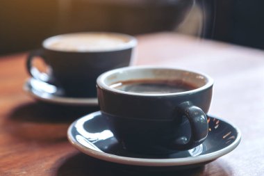 Kafedeki eski ahşap masada iki mavi fincan sıcak kahve ve Americano kahvesinin yakın plan görüntüsü.