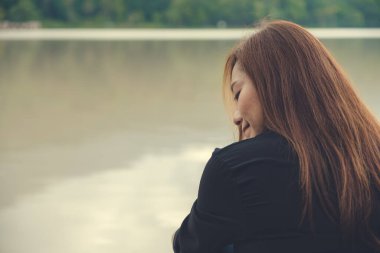 Yakından bakınca Asyalı bir kadının nehir kenarında tek başına oturduğunu görüyoruz. 
