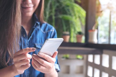 Akıllı bir telefonu tutan, kullanan ve dokunan bir kadının yakın plan görüntüsü