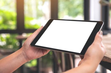 Antika kafede boş masaüstü ekranı olan siyah tableti tutan ellerin görüntüsü