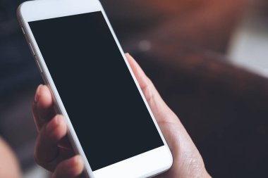 Boş siyah masaüstü ekranı ve bulanık arkaplanı olan beyaz cep telefonunu tutan bir elin görüntüsü
