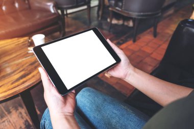 Kafede otururken, ellerinin siyah tableti boş bir masaüstü ekranıyla tutuş görüntüsü