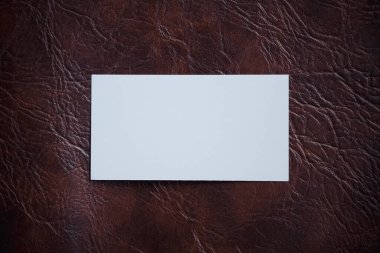 Eski deri arka planda beyaz, boş bir kartvizitin üst görünümü