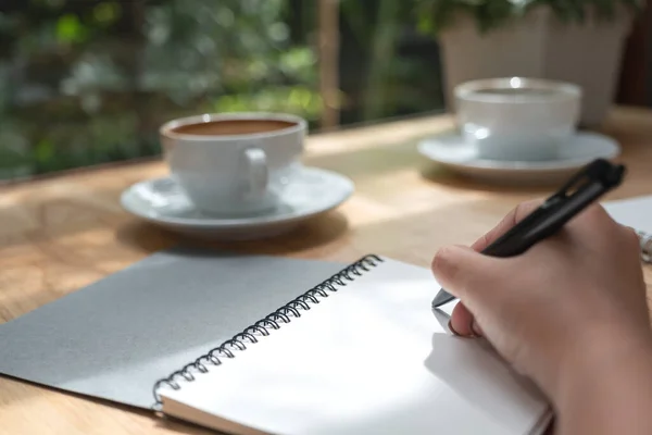 Imagem Close Uma Mão Escrevendo Caderno Branco Branco Com Xícara — Fotografia de Stock