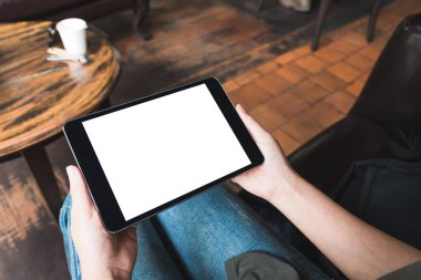 Kafede otururken siyah tableti beyaz masaüstü ekran ile tutan kadınların ellerinin görüntüsü